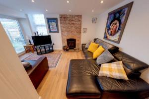 a living room with a leather couch and a fireplace at The Coach House in Westoe