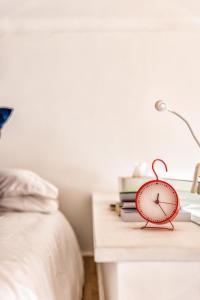a red alarm clock sitting on a table next to a bed at Loft Crocetta in Turin