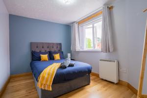 Un dormitorio con una cama con paredes azules y una ventana en Kirsty's Home Near Alton Towers, en Rocester