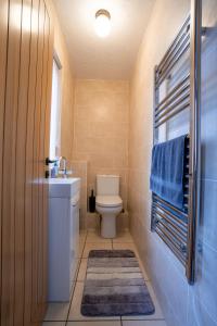 a bathroom with a toilet and a sink and blue towels at Kirsty's Home Near Alton Towers in Rocester