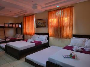 een hotelkamer met 2 bedden en oranje gordijnen bij Rooms R Us - Voyagers Palace in Puerto Princesa City