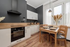 une cuisine avec des placards blancs et une table en bois dans l'établissement Norwida Apartment with Balcony Downtown Wrocław by Renters, à Wrocław