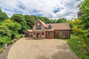 a brick house with a gravel driveway at Woodland Pytchley in West Runton