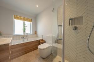 a bathroom with a toilet and a tub and a shower at Castle Bungalow in Thornham +22 photos