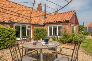 a table and chairs in front of a house at Castle Bungalow in Thornham