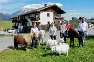 um grupo de pessoas na relva com animais em Studlerhof em Oberperfuss