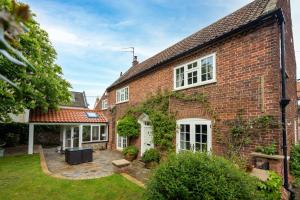 an exterior view of a brick house with a courtyard at The Old Manor House in Brancaster
