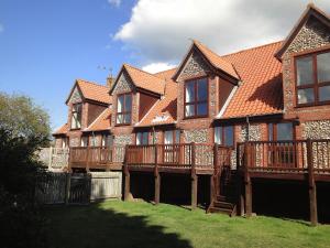 a large brick house with a deck on a yard at The Saltings Blakeney in Blakeney