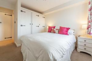 a bedroom with a large white bed with pink pillows at The Saltings Blakeney in Blakeney