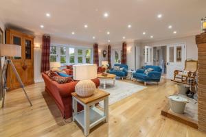a living room with a red couch and blue chairs at Waterside in Wiveton