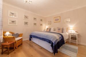 a bedroom with a bed and a chair and pictures on the wall at Waterside in Wiveton