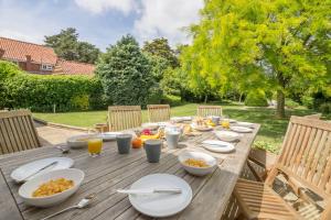 une table en bois avec des assiettes de nourriture dessus dans l'établissement Westgate Cottage Thornham, à Thornham
