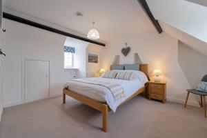 um quarto com uma cama grande e paredes brancas em Twitchers Cottage em Titchwell
