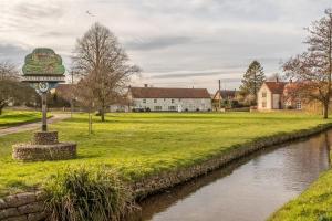 a park with a river in front of a building at Cornloft Cottage in South Creake