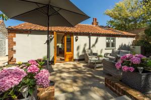 a patio with an umbrella and purple flowers at The Old Chapel W in Little Walsingham