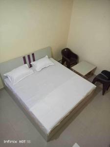 - un lit blanc avec 2 chaises dans une chambre dans l'établissement OYO Hotel Sky View 1, à Moradabad
