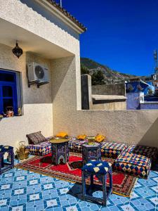 eine Terrasse mit Sofas und Tischen an der Seite eines Hauses in der Unterkunft Hôtel Al Kalaa in Chefchaouen