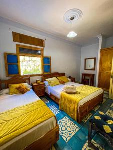 a bedroom with two beds and a window at Hôtel Al Kalaa in Chefchaouene