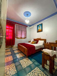 Schlafzimmer mit einem Bett und einem roten Fenster in der Unterkunft Hôtel Al Kalaa in Chefchaouen