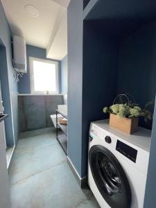 uma máquina de lavar roupa num quarto com uma parede azul em Voyage Penthouse em Tirana
