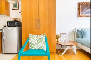 a room with a blue chair with a table and a refrigerator at Staycation in Manila (2 min. walk to Robinson's) in Manila +12 photos