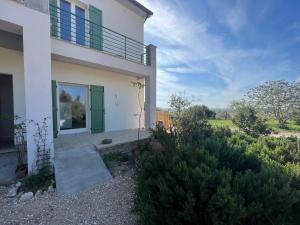 ein weißes Haus mit grüner Tür und einigen Büschen in der Unterkunft Agriturismo Casette del Forno in Montalto di Castro