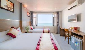 a hotel room with two beds and a desk at Arise Seaside Hotel in Nha Trang