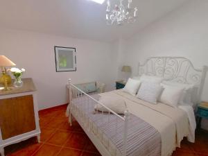 a bedroom with a white bed and a chandelier at A Casa Pequenina - Escusa, Marvão in Marvão