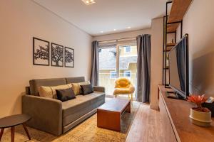 een woonkamer met een bank en een televisie bij Rosa Edifício Reservas das Orquídeas in Gramado