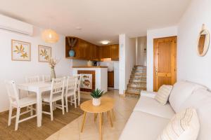 a living room and kitchen with a white couch and a table at Binilaya in Sant Lluis