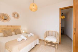 a bedroom with two beds and a chair at Binilaya in Sant Lluis