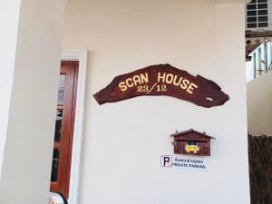 een teken voor een huis aan een muur bij Scan House Apartment in Karon Beach