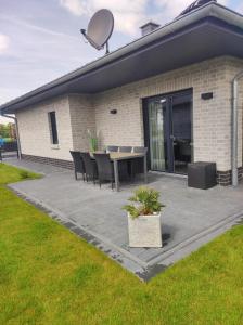 a patio with a table and chairs in front of a house at Ferienhaus Luna am schönen Harkebrügger See mit Kamin und Sauna in Barßel