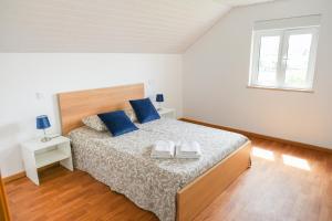 a white bedroom with a large bed with blue pillows at Casa Vilar in Ponte de Lima