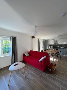 a living room with a red couch and a table at Gite Terrasse Le Doux Refuge à Beblenheim Parking privé in Beblenheim