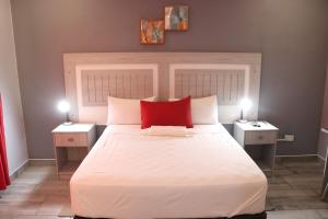 a bedroom with a large white bed with a red pillow at Amariah Lodge in Kasane