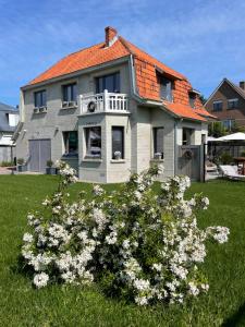 a house with a bunch of flowers in the yard at B&B Villa Navy in Koksijde