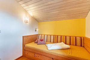 Cama pequeña en habitación con pared amarilla en Ferienwohnung Geierstein en Wackersberg