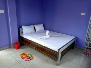 a bed in a purple room with a plate of fruit on the floor at Hotel Priyal Inn in Bokāro