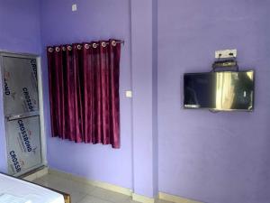 um quarto com uma cortina vermelha e uma televisão na parede em Hotel Priyal Inn em Bokāro