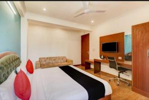 a bedroom with a bed and a desk and a tv at OYO Admi Suites in New Delhi