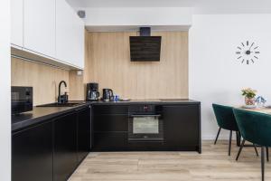 a kitchen with black cabinets and a table with green chairs at Apartamenty Sunset Resort by Renters in Grzybowo