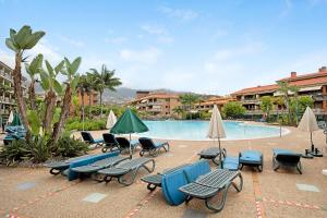a swimming pool with chairs and umbrellas and a group at Casa Fran in Puerto de la Cruz