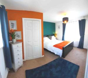 a bedroom with a bed and an orange wall at Pretty Neyland Cottage central to all attractions in Milford Haven