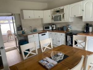 a kitchen with white cabinets and a table and chairs at Pretty Neyland Cottage central to all attractions in Milford Haven