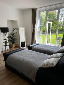 two beds in a bedroom with a large window at No.1 Beechcroft in Liverpool