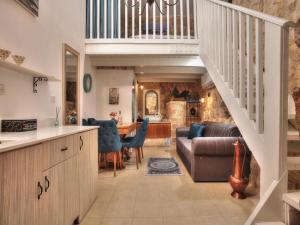 a kitchen and living room with a staircase and a couch at אבני החושן - סוויטות יוקרה בצפת העתיקה - Avnei Hachoshen - Luxury Suites in the Old City in Safed