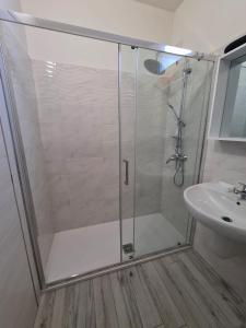 een douche met een glazen deur naast een wastafel bij Civico 14 Apartment 01 in Monserrato