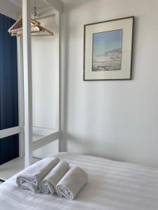 ein weißes Schlafzimmer mit einem Bett mit Handtüchern darauf in der Unterkunft North Sea Spirit in Zandvoort