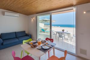 a living room with a table and chairs with a view of the ocean at Appartamenti Sud Est in Marina di Ragusa